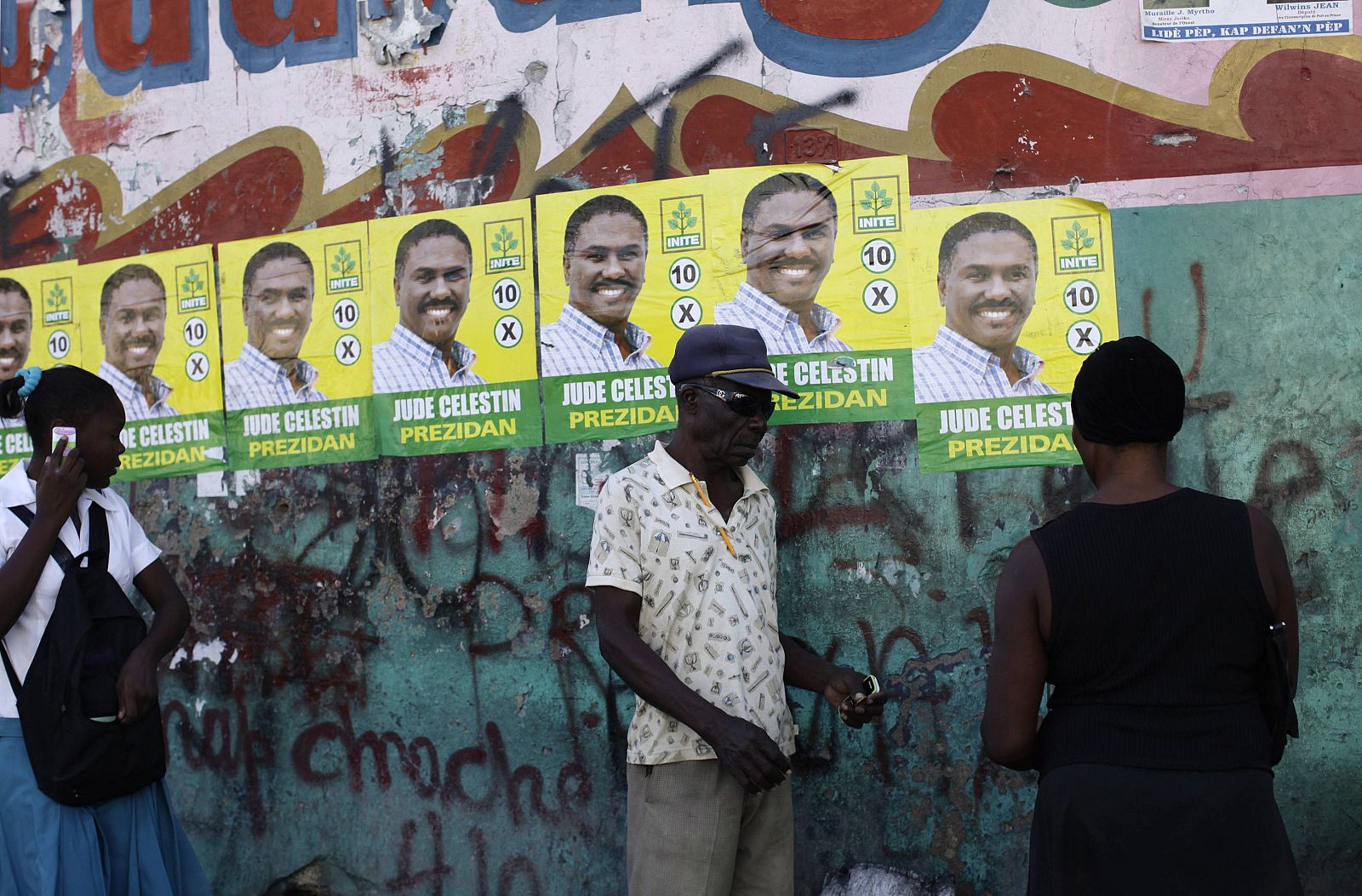 Un grupo de haitianos pasa junto a carteles de Celestin en Puerto Príncipe.