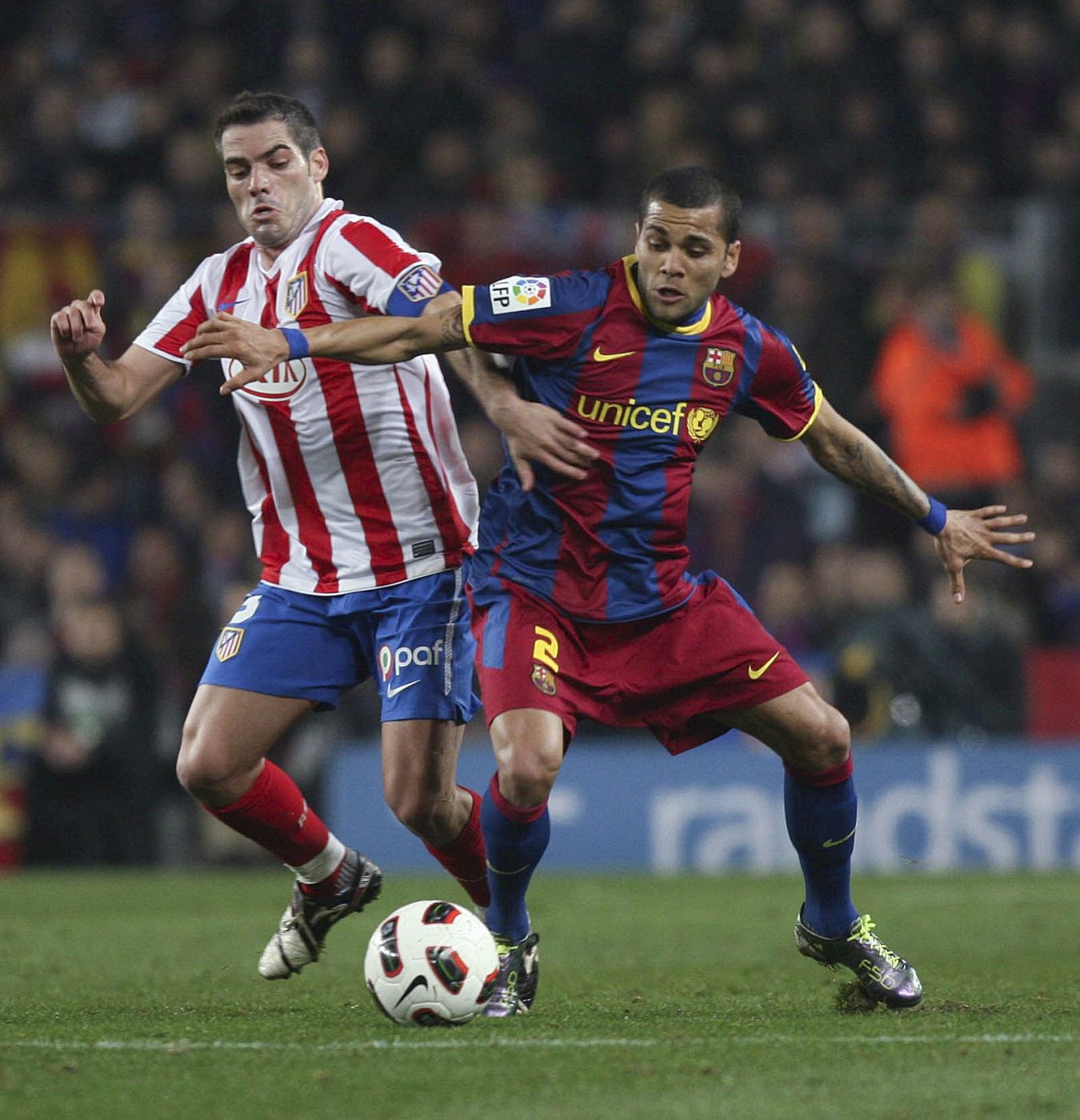 Dani Alves (d) pelea por el balón con el defensor del Atlético de Madrid Antonio López