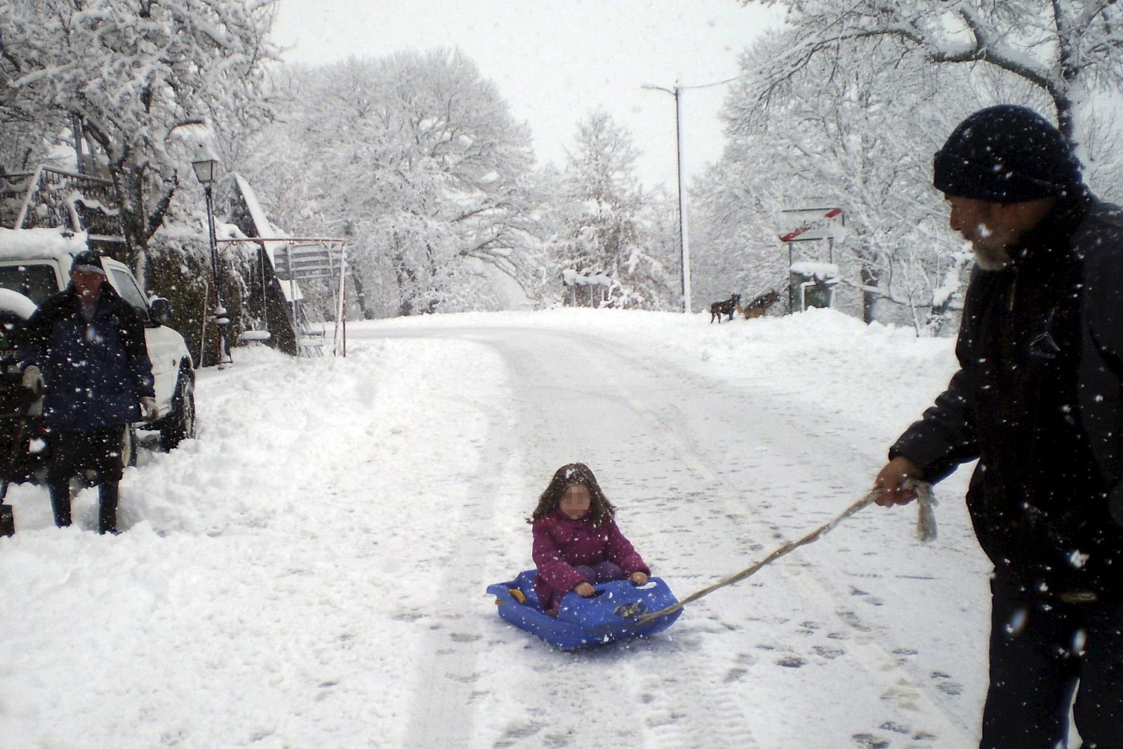 Un hombre juega con su hija en un trineo tras suspender las clases el colegio por la nieve en Lubián (Zamora)