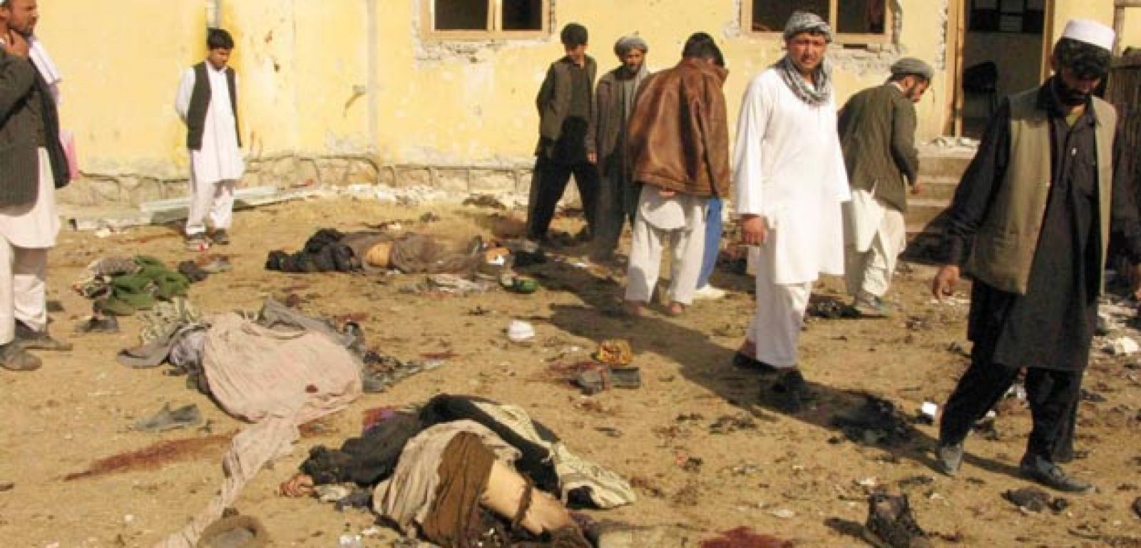 Un grupo de afganos observan los cadáveres de dos de las víctimas del ataque suicida registrado en un centro administrativo del Gobierno afgano en la provincia de Kunduz, en el norte de Afganistán