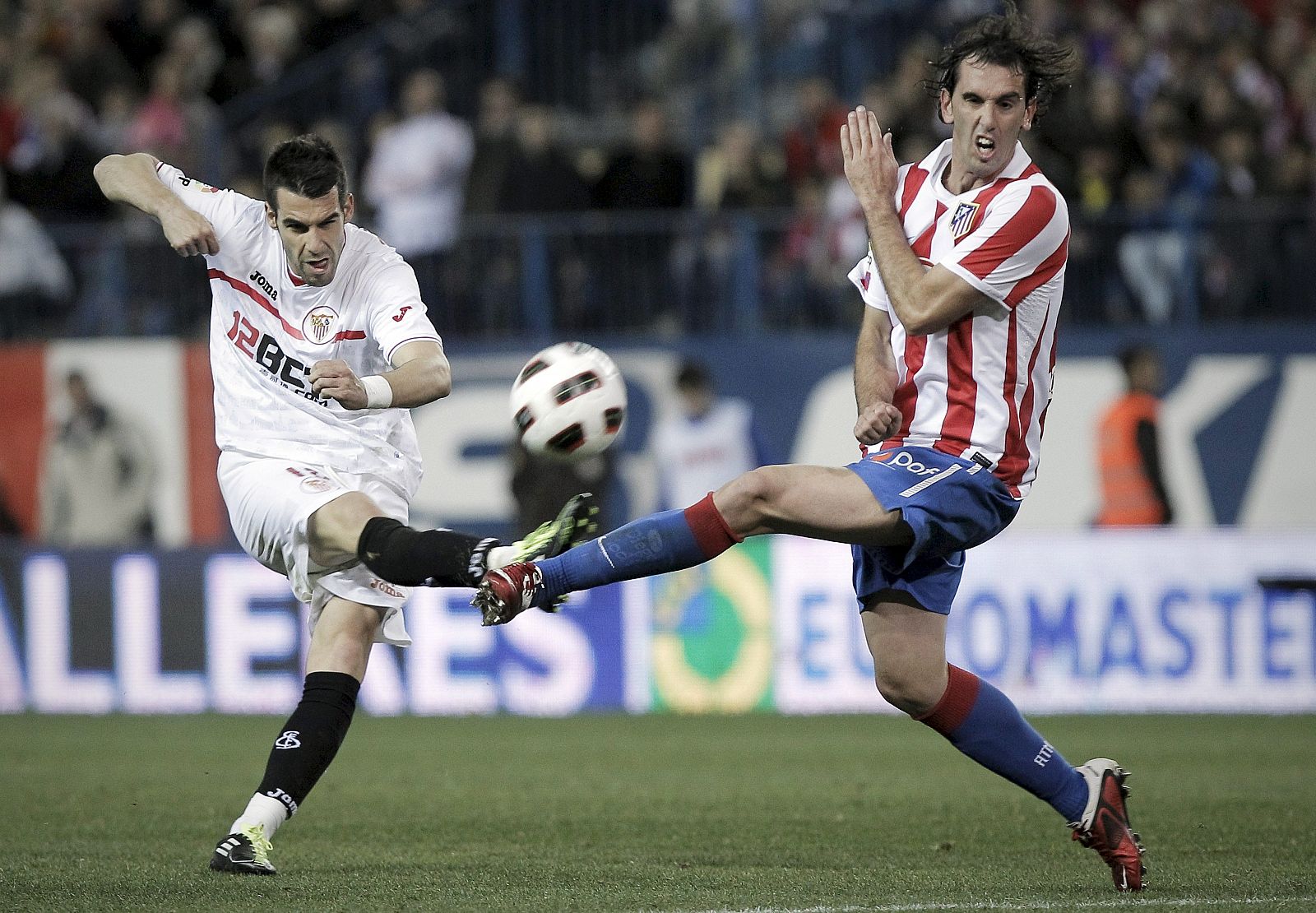 Álvaro Negredo (i) chuta a portería ante el defensa uruguayo del Atlético de Madrid Diego Godín.