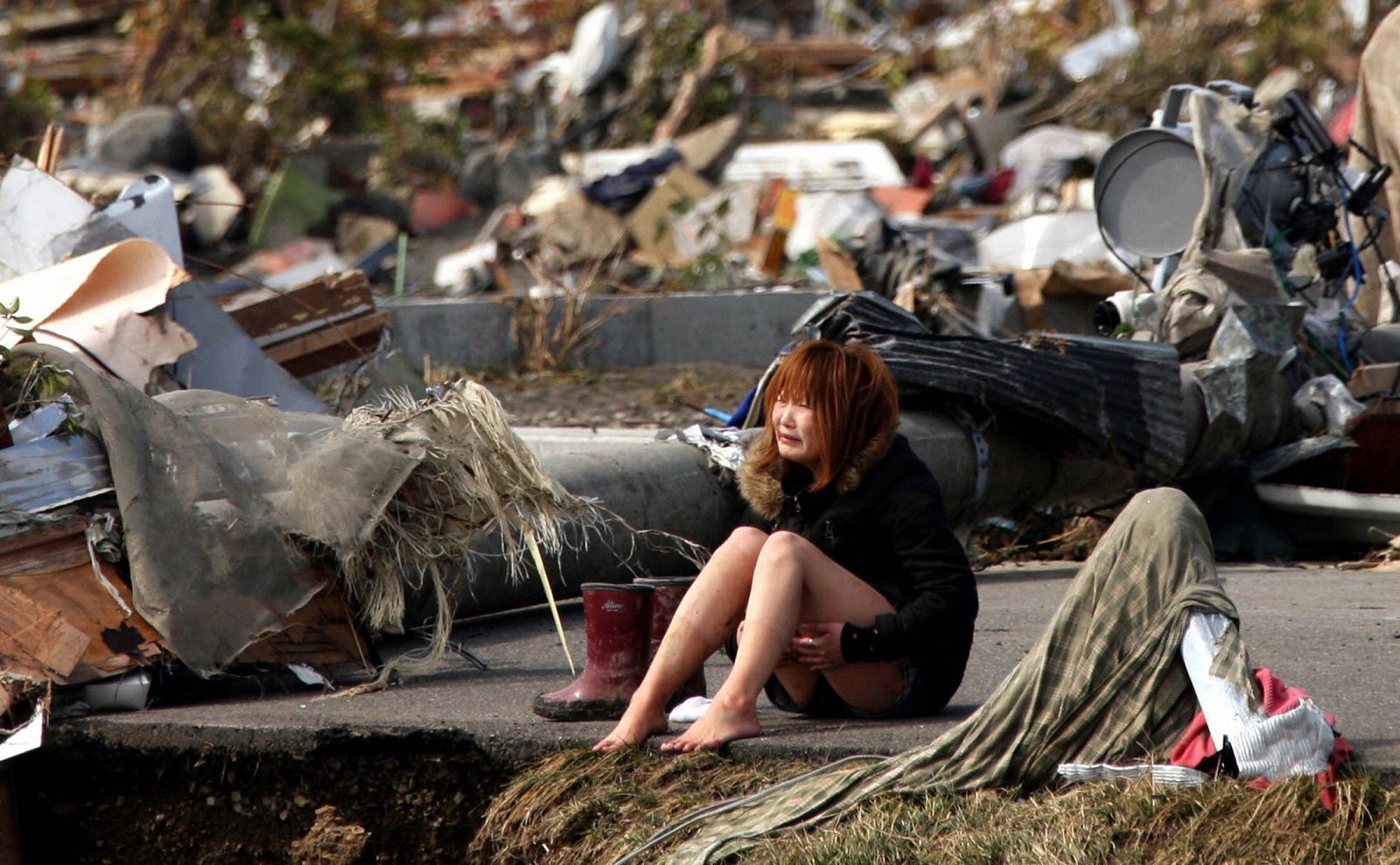 Una mujer llora sentada en una carretera de Natori, una de las ciudades más afectadas por el terremoto de Japón