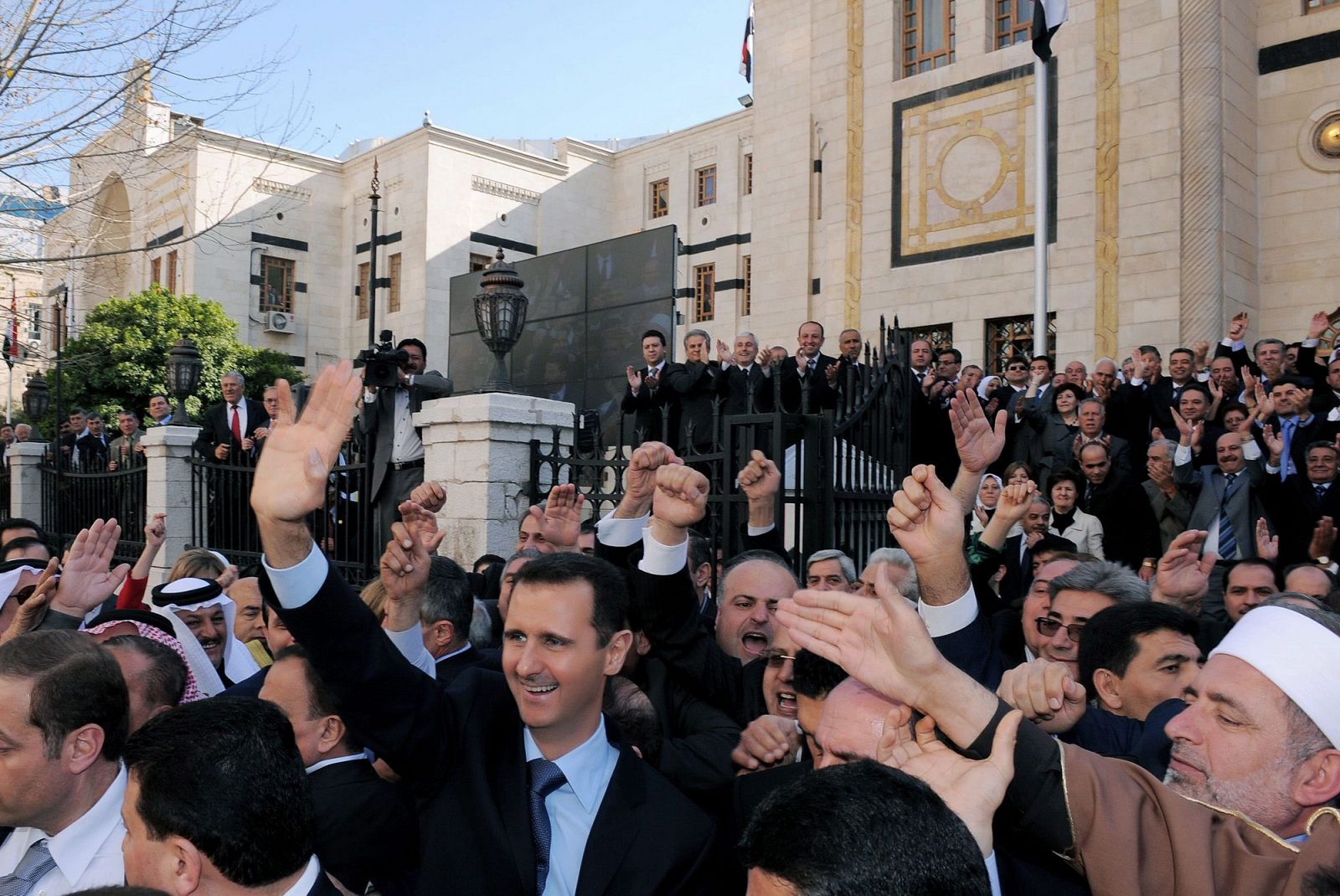 El presidente de Siria Bashar Assad saluda a la multitud tras dejar el parlamento sirio luego de dirigirse a la nación en Damasco