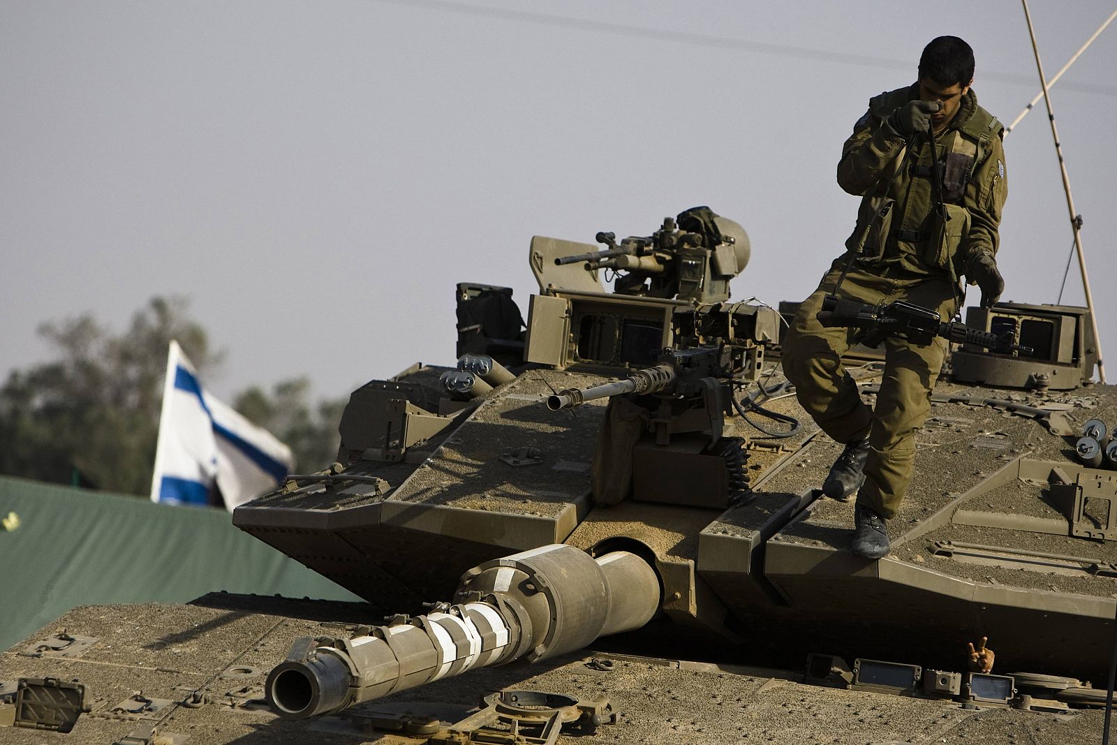 An Israeli soldier stands on his tank near kibbutz Kerem Shalom just outside the southern Gaza Strip