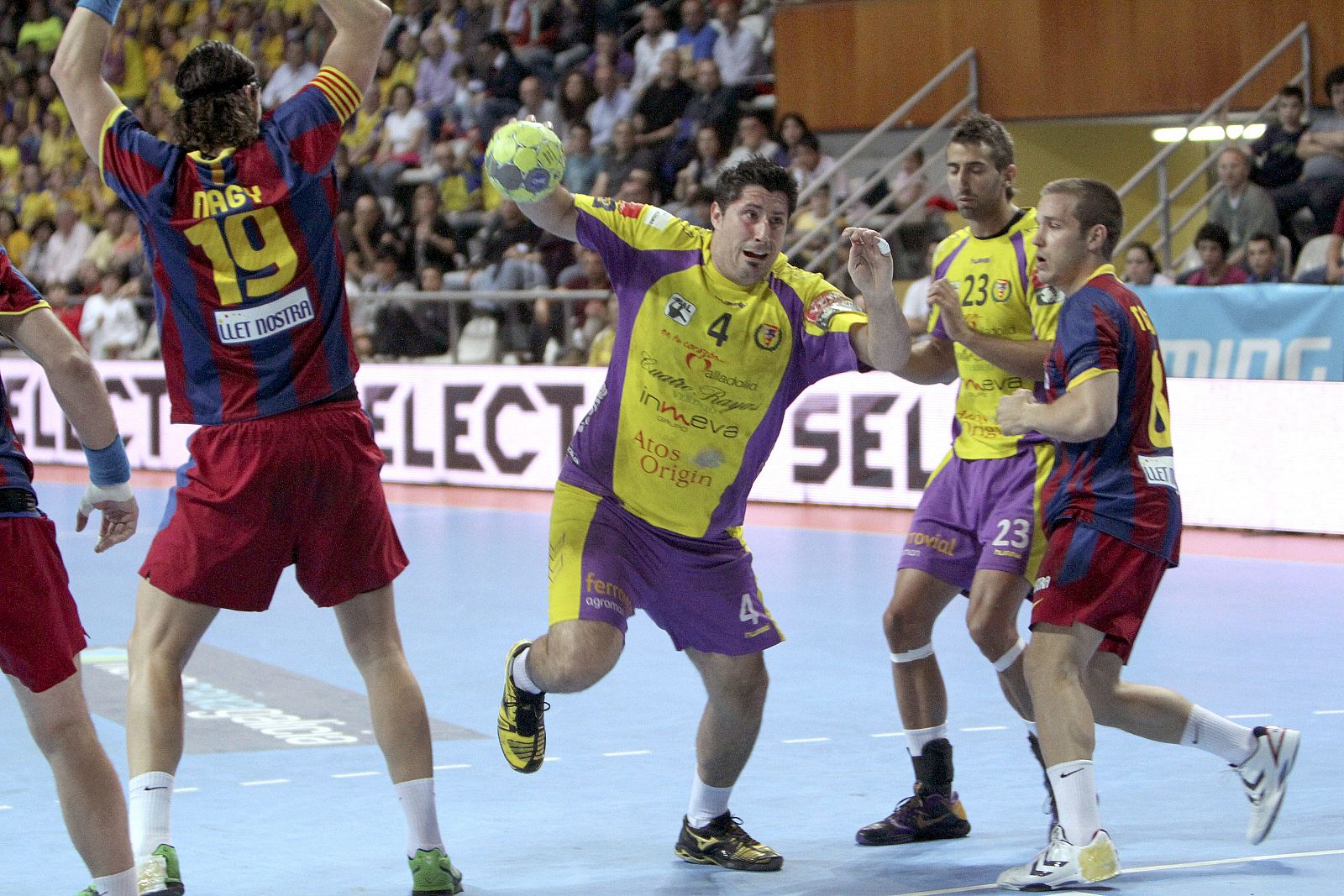 El pivote del Cuatro Rayas Valladolid Eduard Fernández (c) se dispone a efectuar un lanzamiento entre los defensas del FC Barcelona Borges.