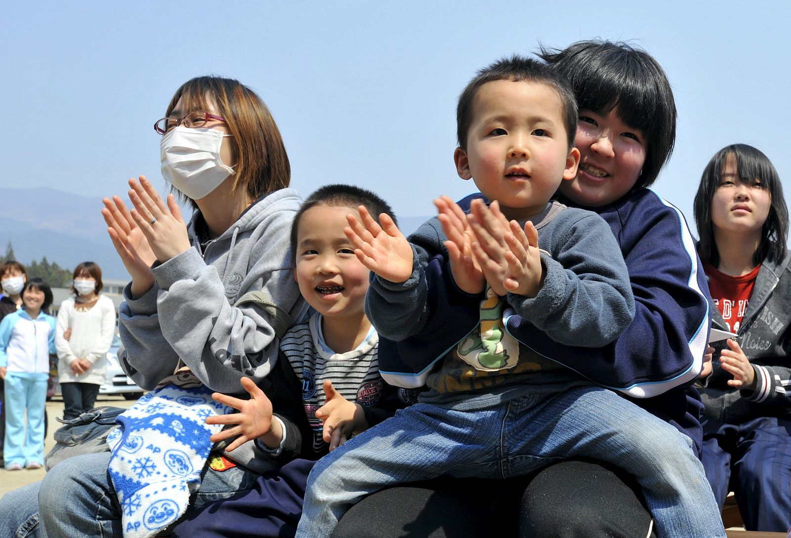 Niños se divierten con la actuación de un mono, en un centro de asistencia de la ciudad japonesa de Rikuzentakata, prefectura de Iwate