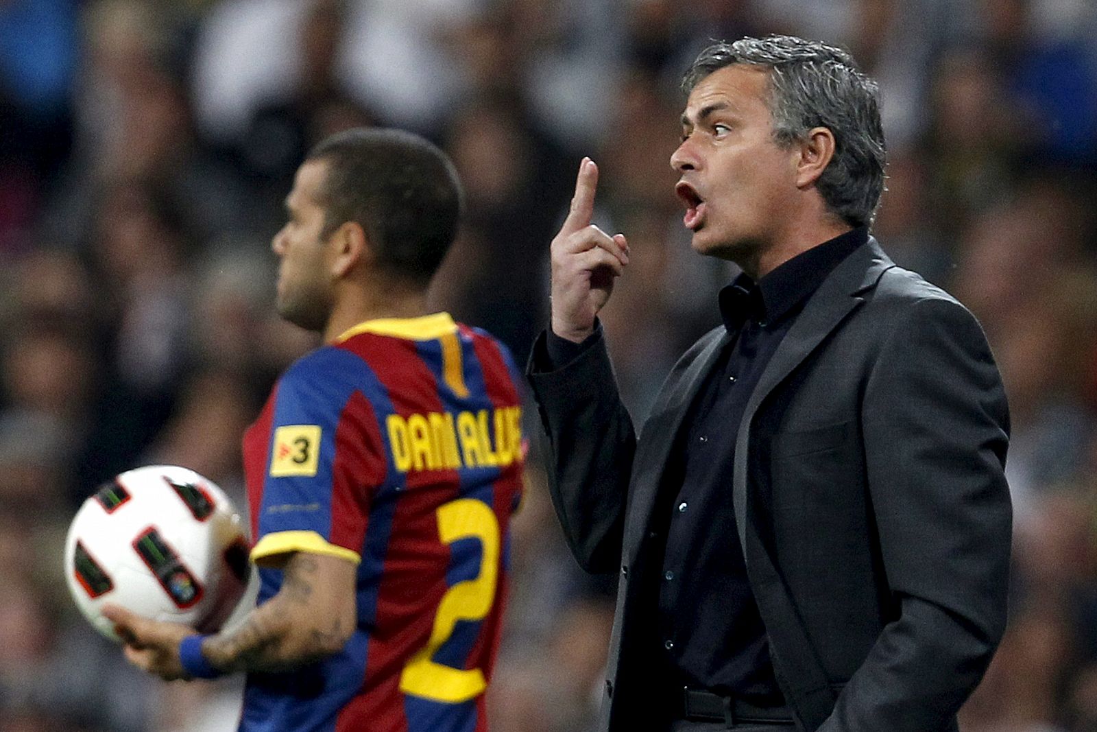 El entrenador del Real Madrid, el portugués José Mourinho da instrucciones desde la banda ante la presencia del defensa brasileño del Barcelona Dani Alves.