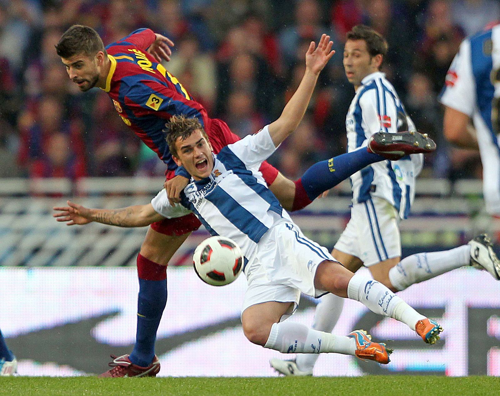 Antoine Griezmann (c) cae ante el agarrón del defensa del FC Barcelona Gerard Piqué (i).