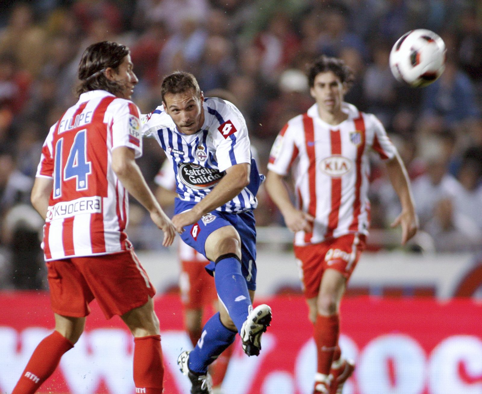 El delantero del Deportivo Xisco (c) chuta ante el brasileño Filipe Luis, del Atlético.