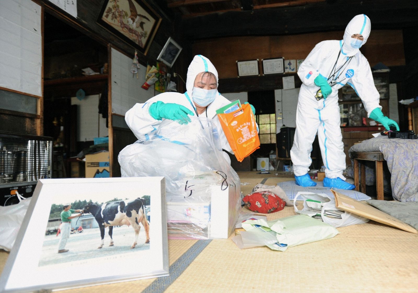 Evacuados de Kawauchi vestidos con trajes protectores recogen sus pertenencias durante una visita de dos horas a su vivienda