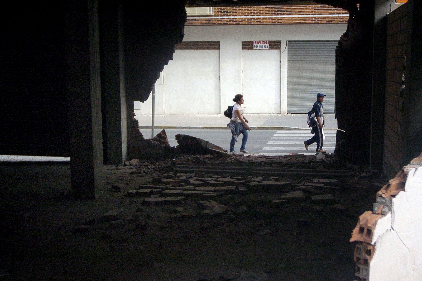 Dos personas caminan junto a los daños materiales causados en un edificio del barrio de San Diego.