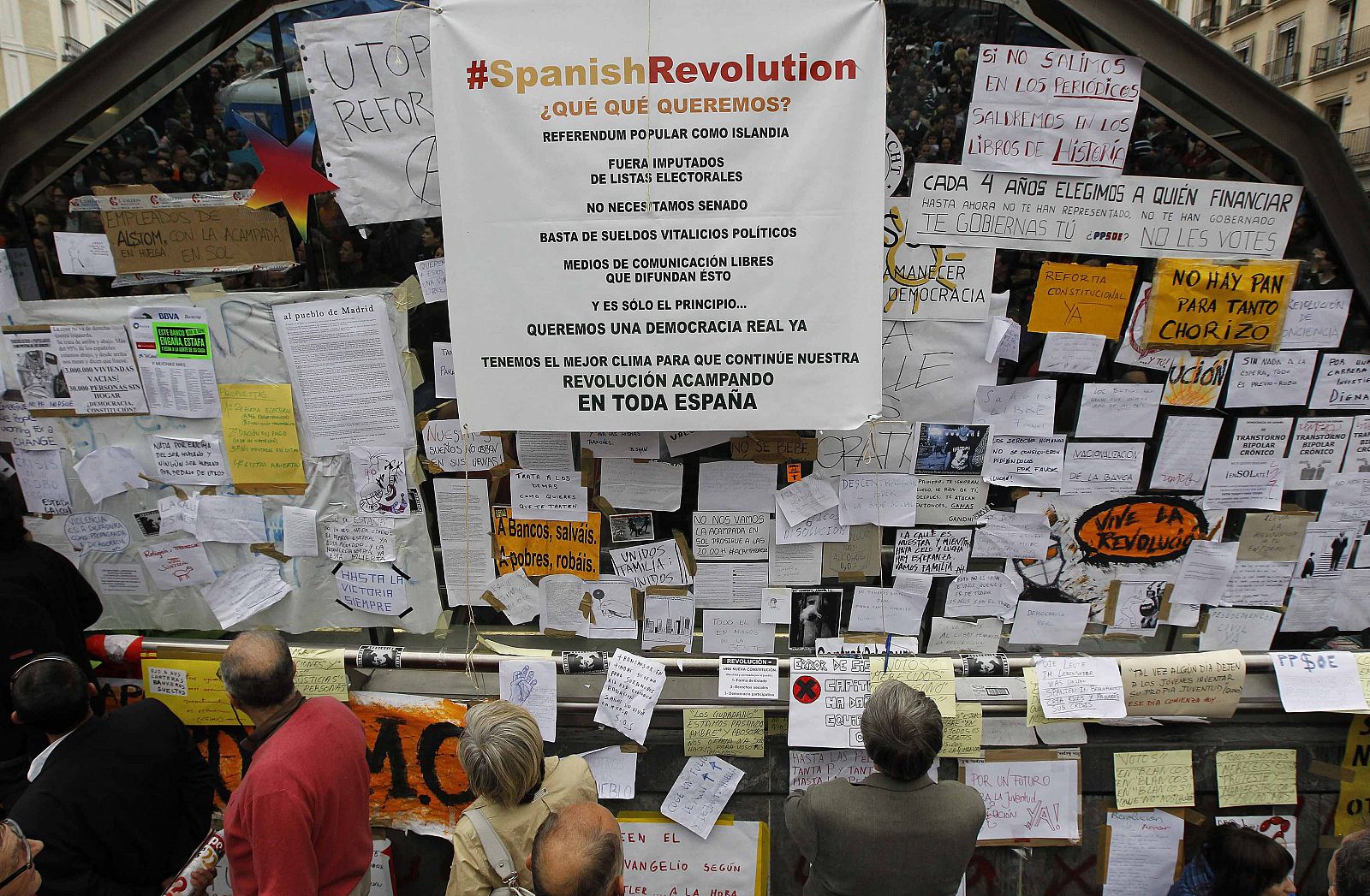 People look at signs put up by demonstrators in Madrid's Puerta del Sol