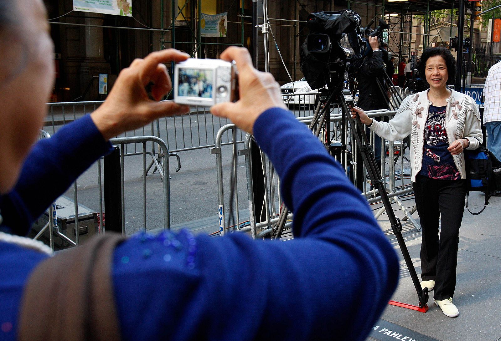 Un turista posa para una foto junto a una cámara de televisión donde está bajo arresto domiciliario Strauss-Kahn.