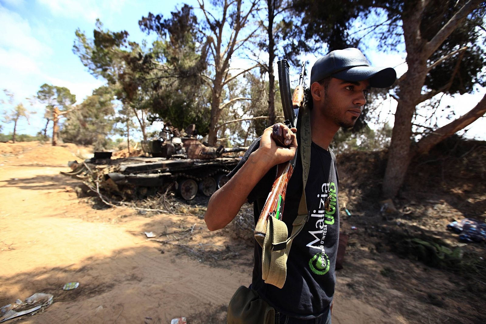 Libyan rebel fighter walks past a destroyed tank belonging to forces loyal to Libyan leader Muammar Gaddafi on the outskirts of Zlitan, near Misrata's western front line