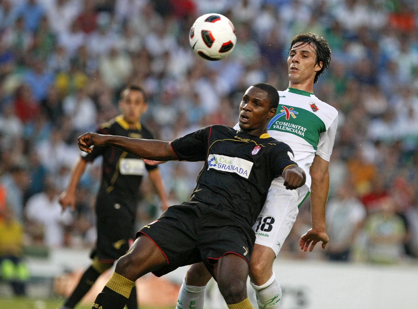 El defensa del Elche Sergio Pelegrín lucha un balón con el delantero nigeriano del Granada Odion Jude Ighalo.