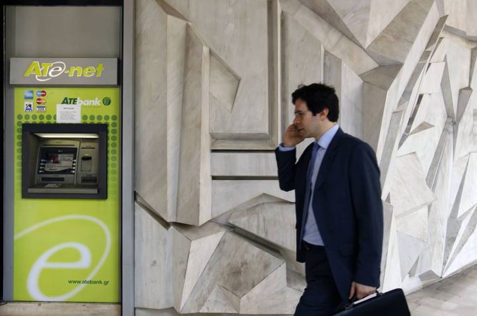 Un hombre camina por delante de una oficina del ATEBank griego, una de las entidades suspensas