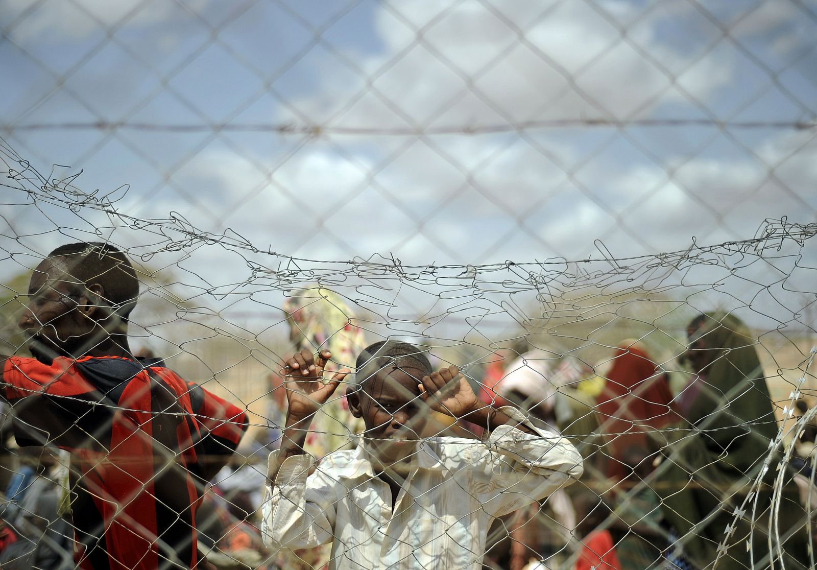 Un niño mira a través de una valla cómo llegan refugiados al campamento de Al Dadaab, en Kenia.