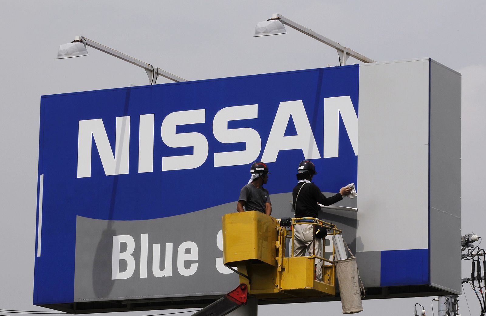 Workers work on a signboard at a Nissan dealer shop in Tokyo