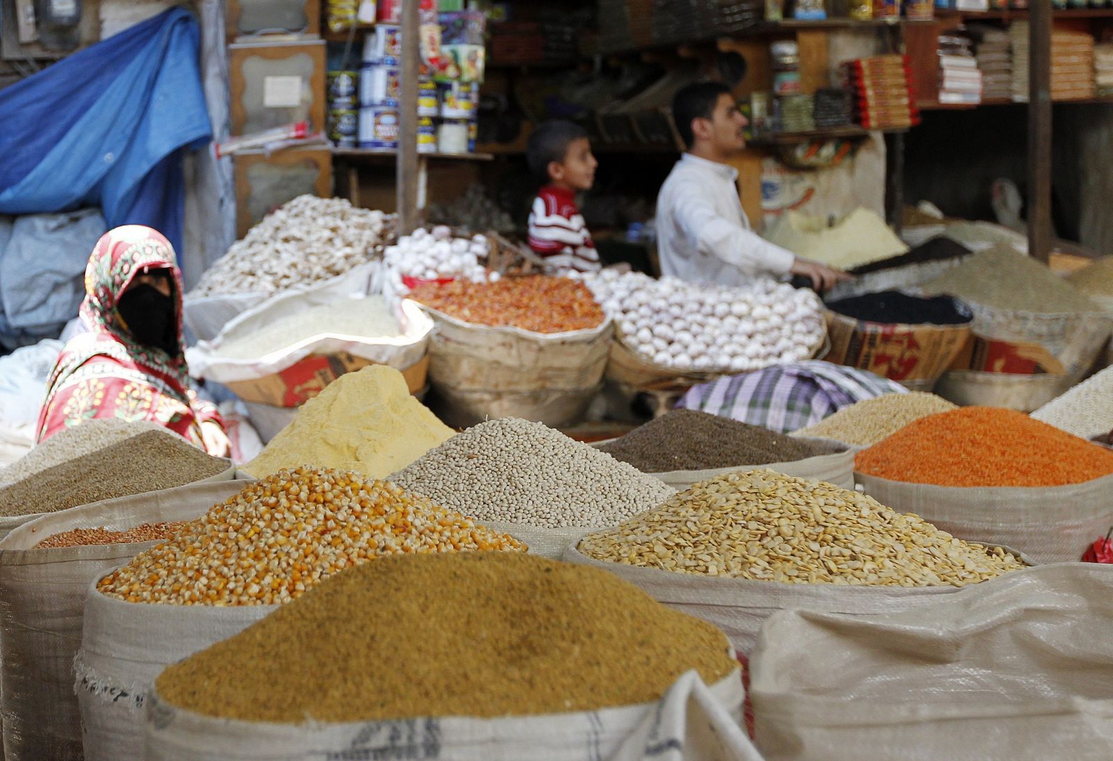 A woman walks past a shop selling spices and vegetables in preparation for the Muslim holy month of Ramadan, in the Old City of Sanaa