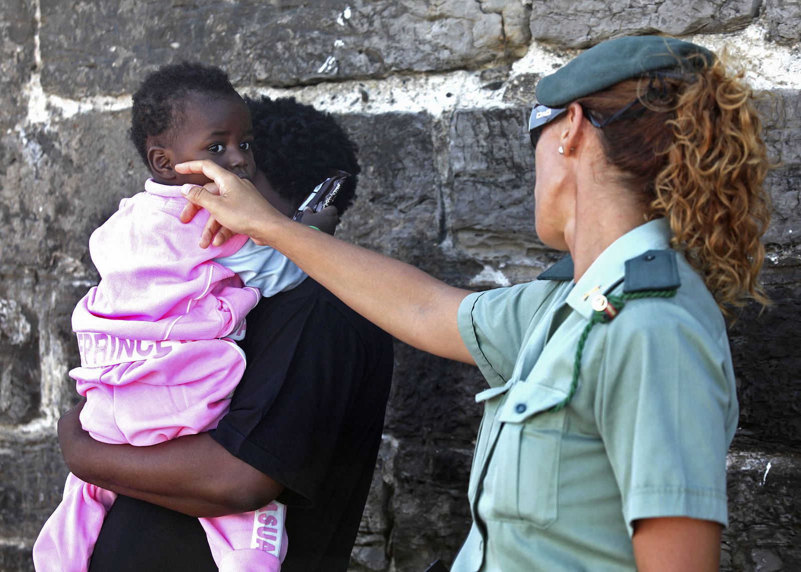 Una guardia civil se interesa por el estado de una bebé interceptada junto a otros 26 subsaharianos a bordo de una patera al sur de Tarifa.