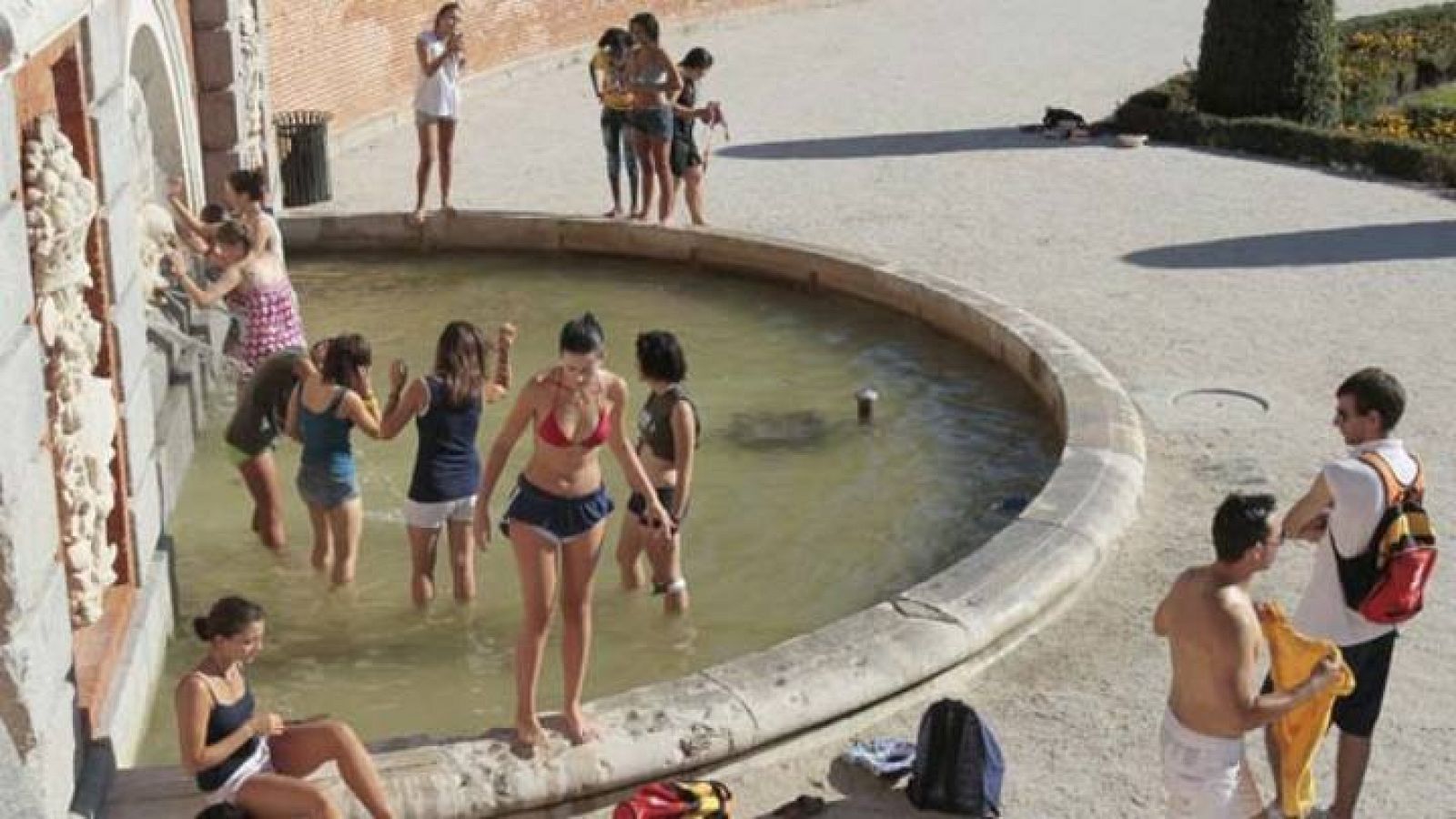 Los peregrinos combaten el calor en una fuente del Parque del Retiro en Madrid