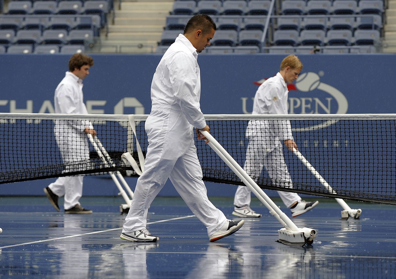 Varios operarios trabajan sobre la pista central del US Open, afectada por la lluvia