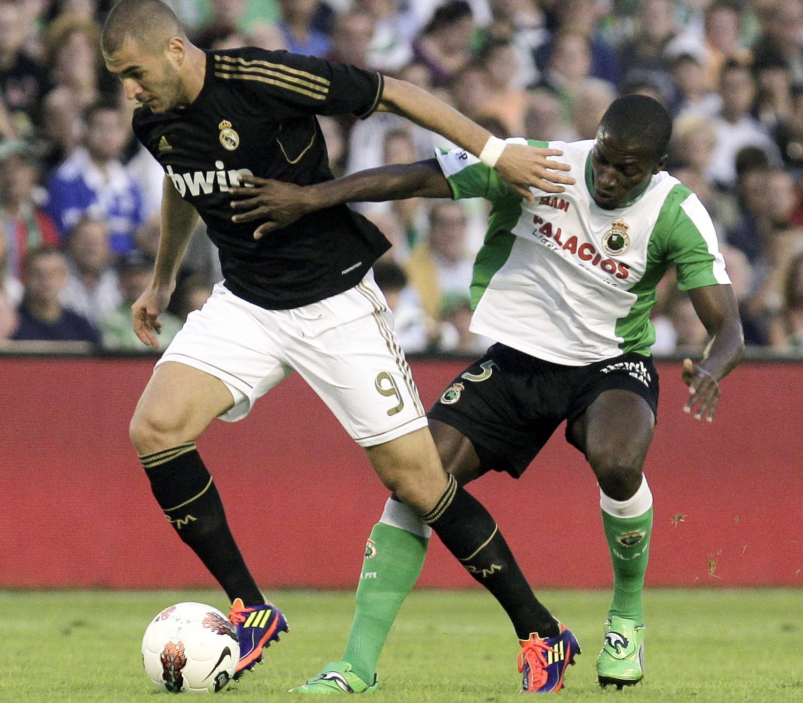 El delantero francés del Real Madrid, Karim Benzema (i) conduce un balón ante la presión del centrocampista senegalés del Racing de Santander, Pape Diop