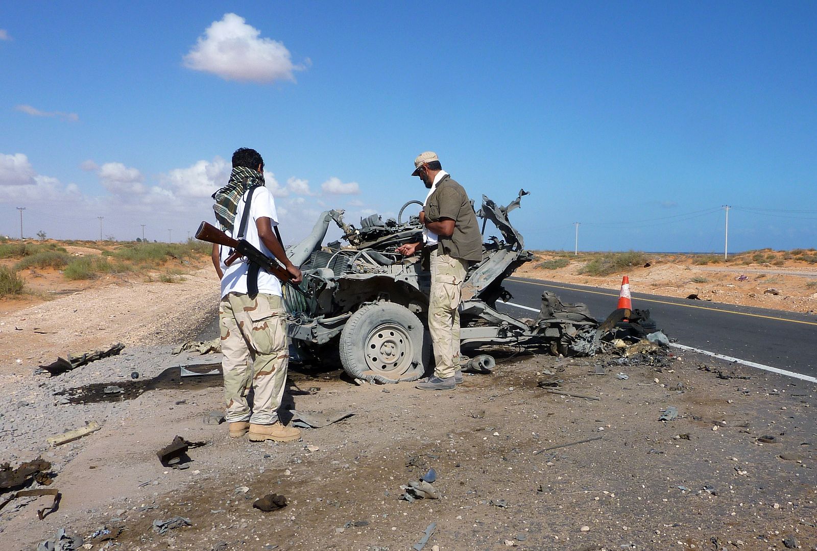 Un grupo de rebeldes libios inspeccionan un vehículo de los gadafistas destrozado por un bombardeo de la OTAN.