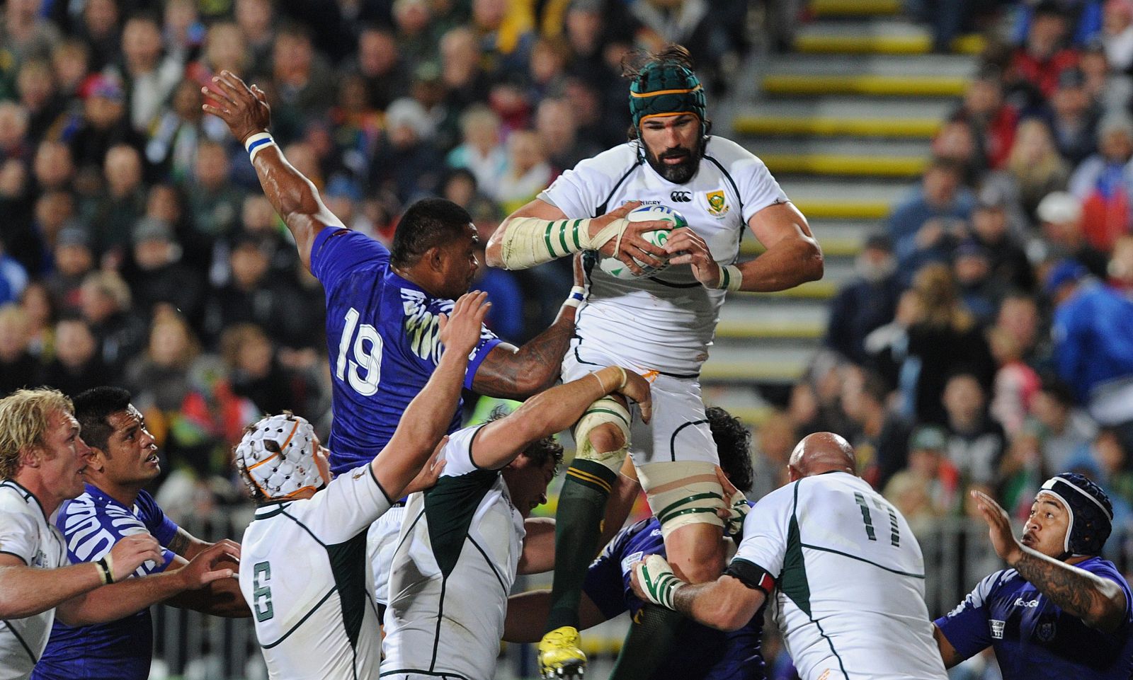 El jugador de Sudáfrica Victor Matfield agarra la pelota en un line-out junto a Ofisa de Samoa.