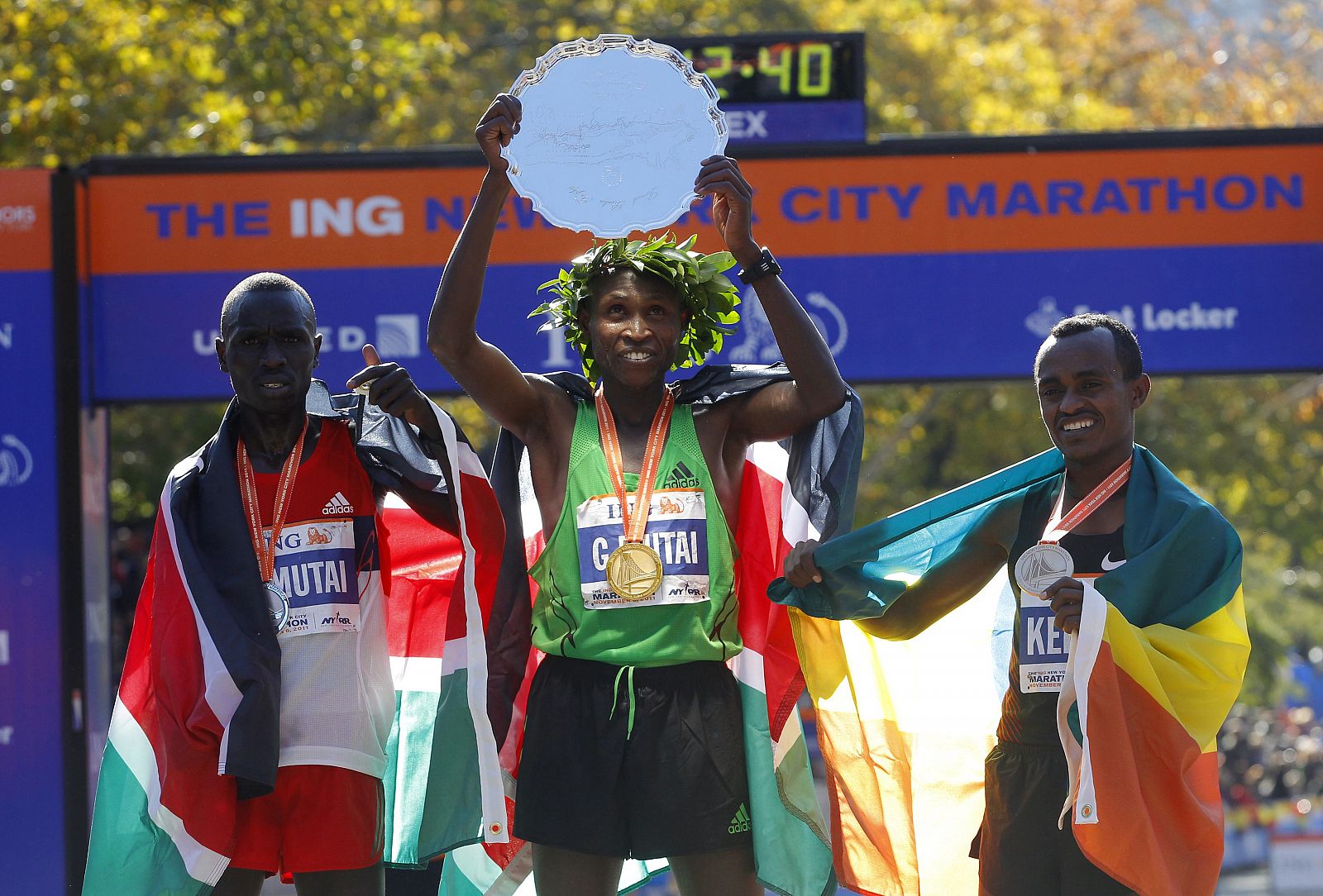 Mutai of Kenya raises the winner's trophy after winning the 2011 New York City Marathon in New York