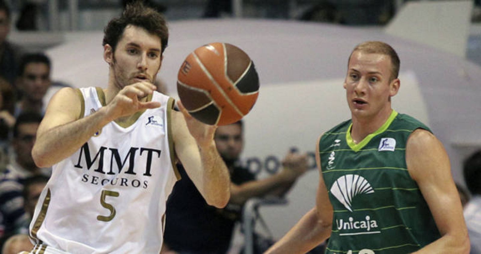 El alero del Real Madrid, Rudi Fernández (i), controla el balón ante la presión del alero croata del Unicaja, Peric.
