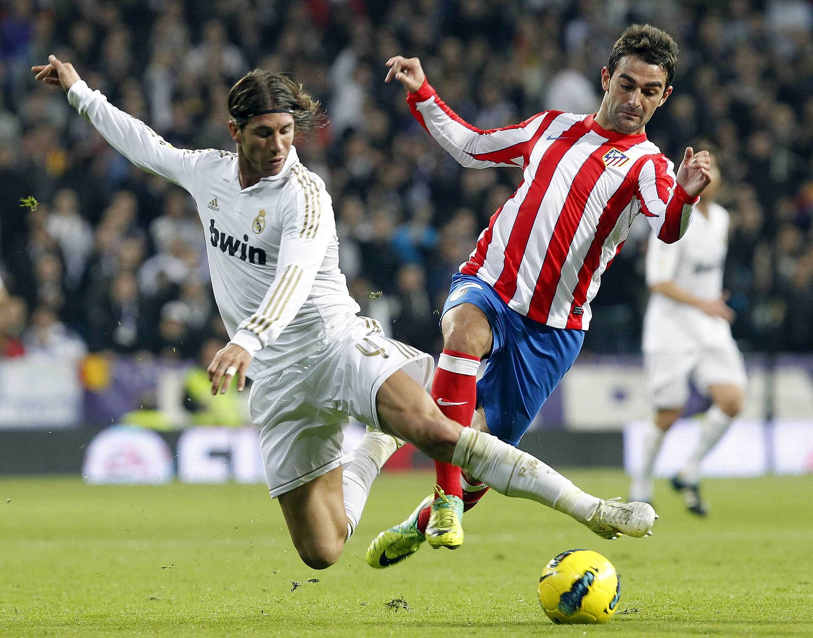 El delantero del Atlético de Madrid Adrián López (d) lucha un balón con el defensa del Real Madrid Sergio Ramos.