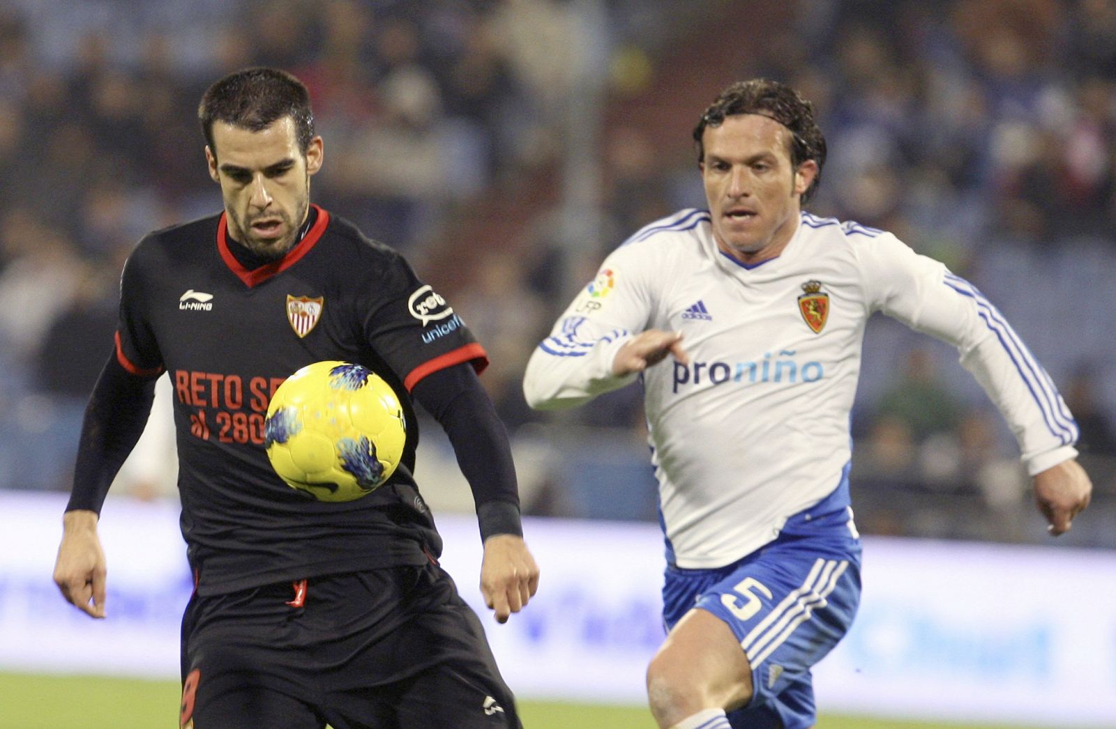 El delantero del Sevilla FC, Álvaro Negredo (i), intenta marcharse del defensa italiano del Real Zaragoza, Maurizio Lanzaro.