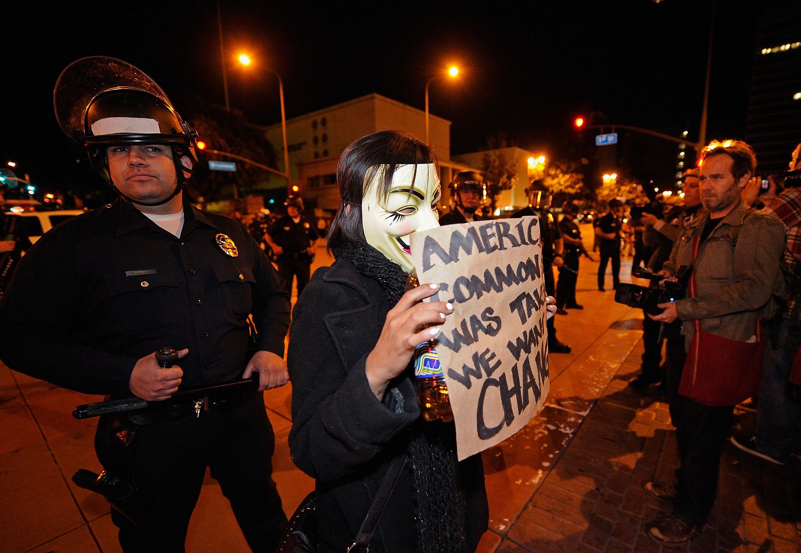 Un policía de Los Ángeles observa a uno de los activistas que se han concentrado en el parque del ayuntamiento para evitar el desalojo del campamento de Occupy