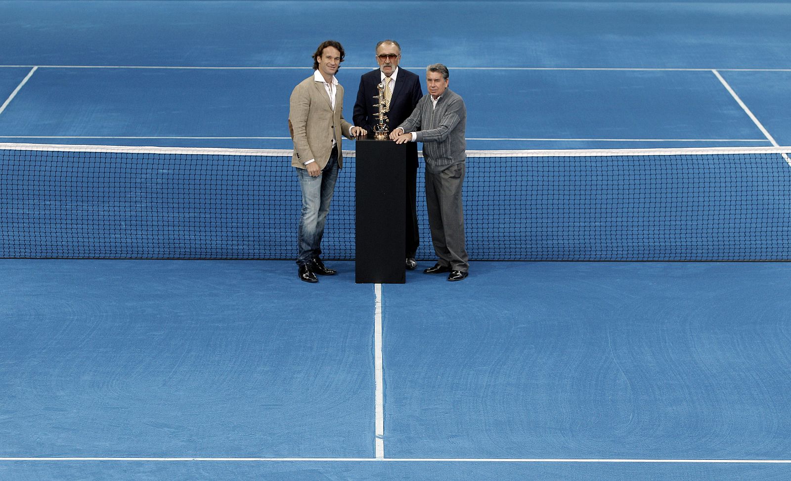 Ion Tiriac, Carlos Moyá y Manolo Santana posan en la presentación de la pista azul