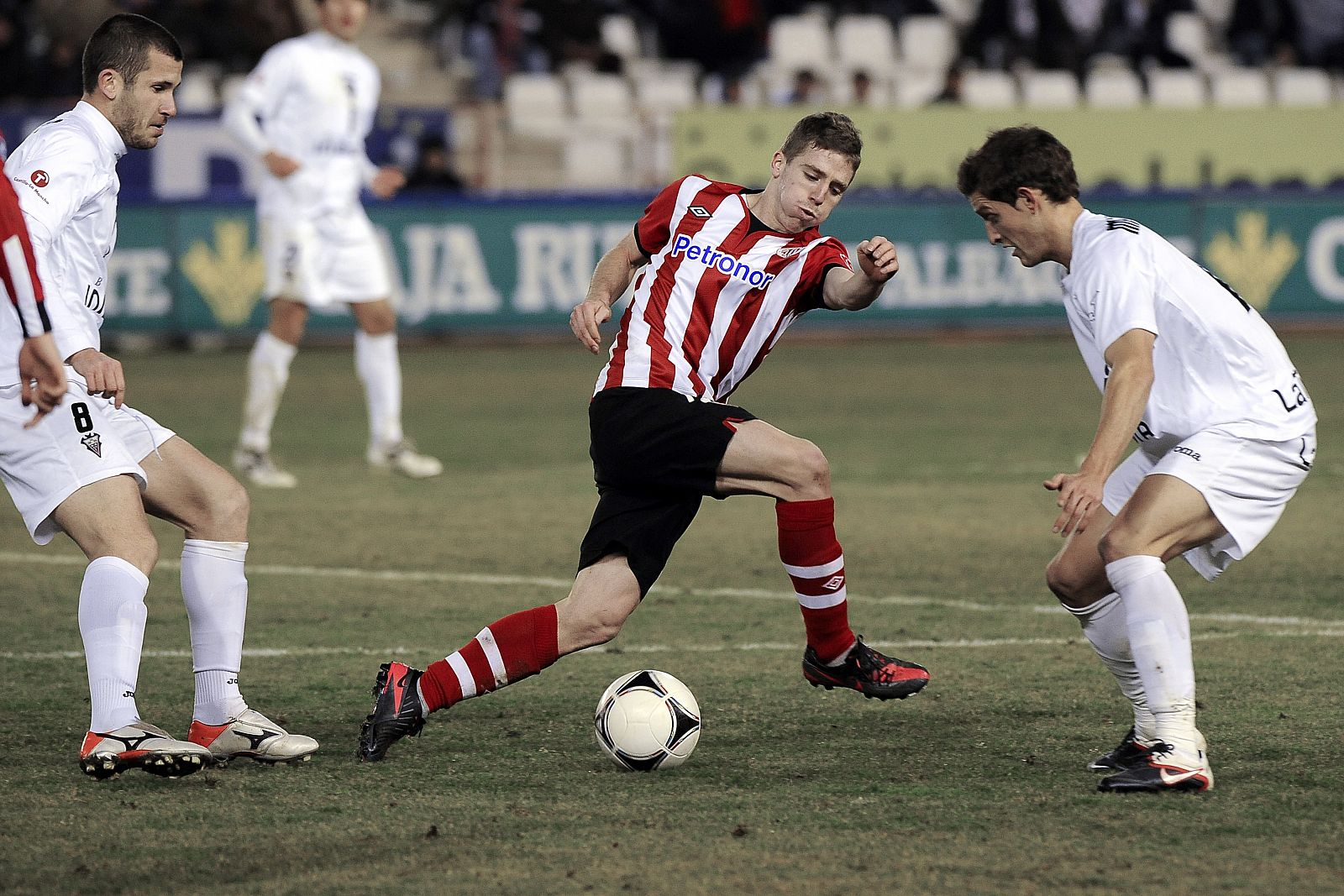 Muniain intenta llevarse el balón ante los jugadores del Albacete Colorado y Núñez.