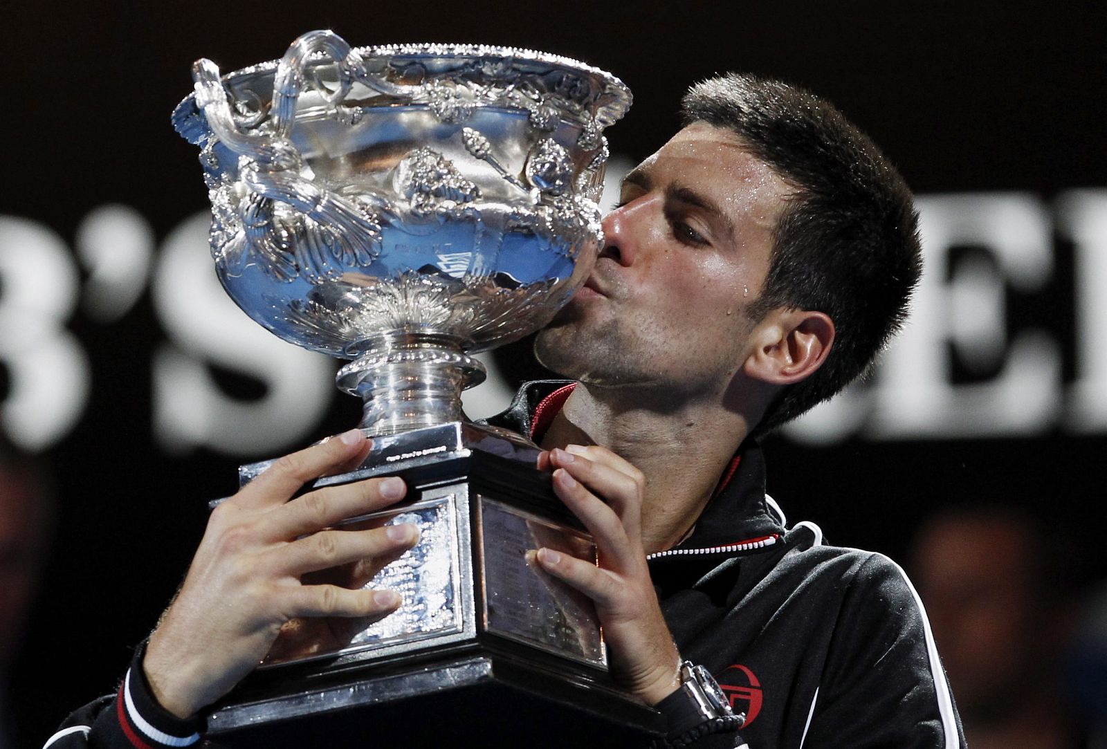 El tenista serbio Novak Djokovic besa el trofeo del Abierto de Australia después de la final que disputó contra el español Rafa Nadal