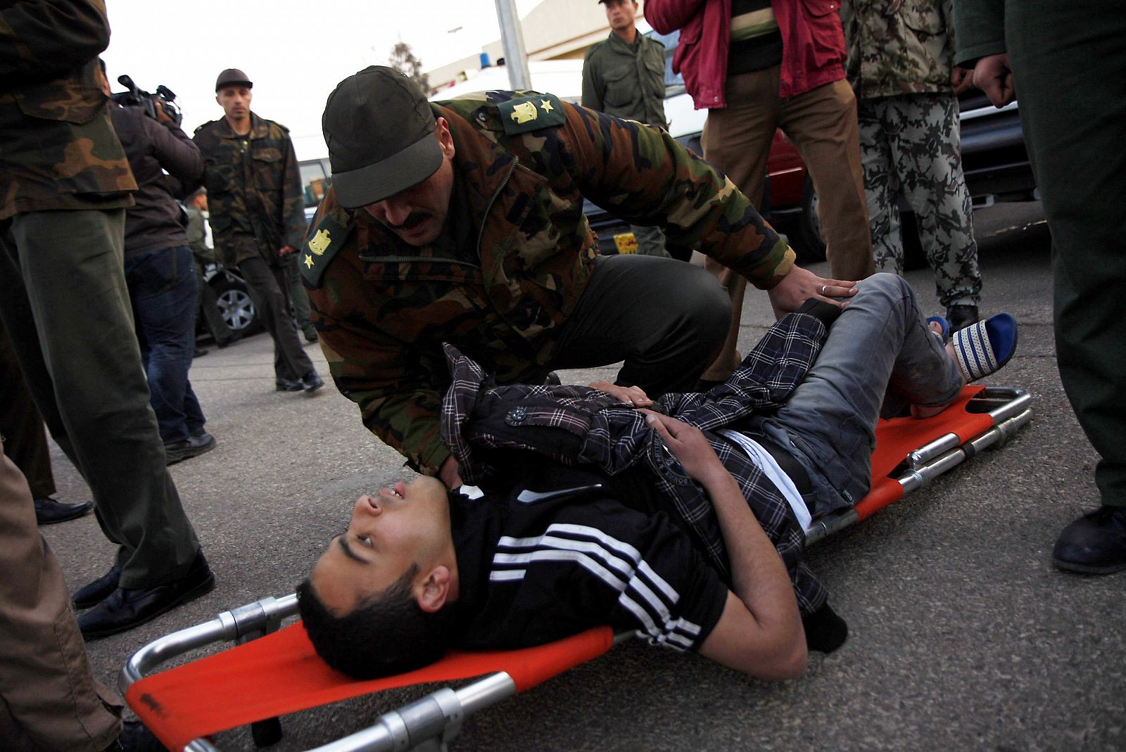 Un soldado egipcio comprueba el estado de uno de los aficionados herido en los incidentes de Port Said a su llegada a El Cairo