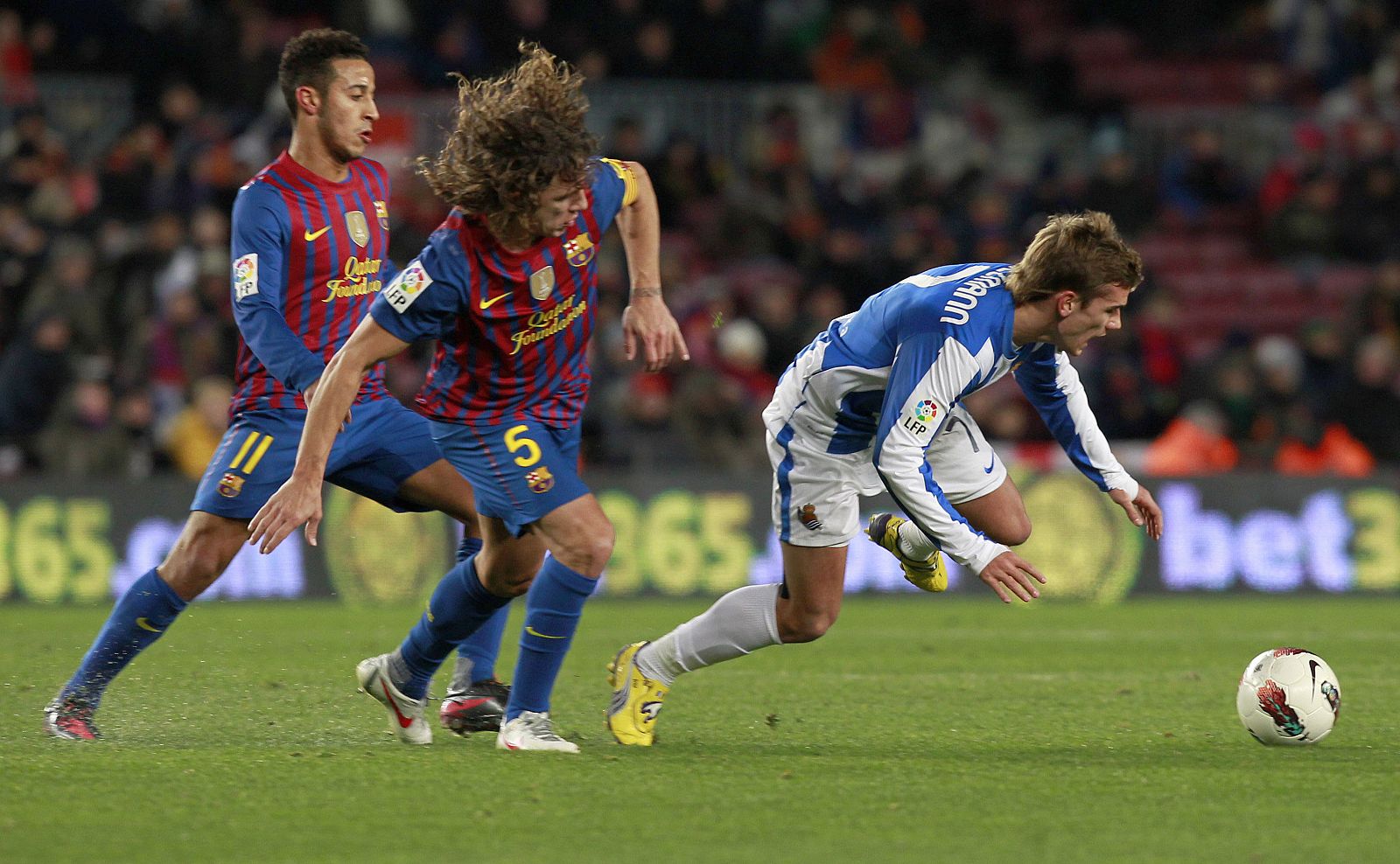 El centrocampista francés de la Real Sociedad Griezmann cae ante Puyol (c) y Thiago (i), del FC Barcelona.