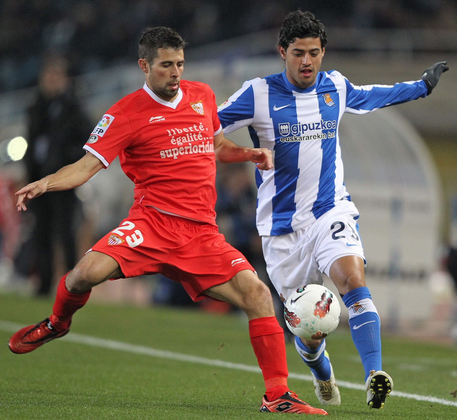 El defensa del Sevilla Jorge Andujar pugna por un balón ante el mexicano de la Real Sociedad Carlos Vela.