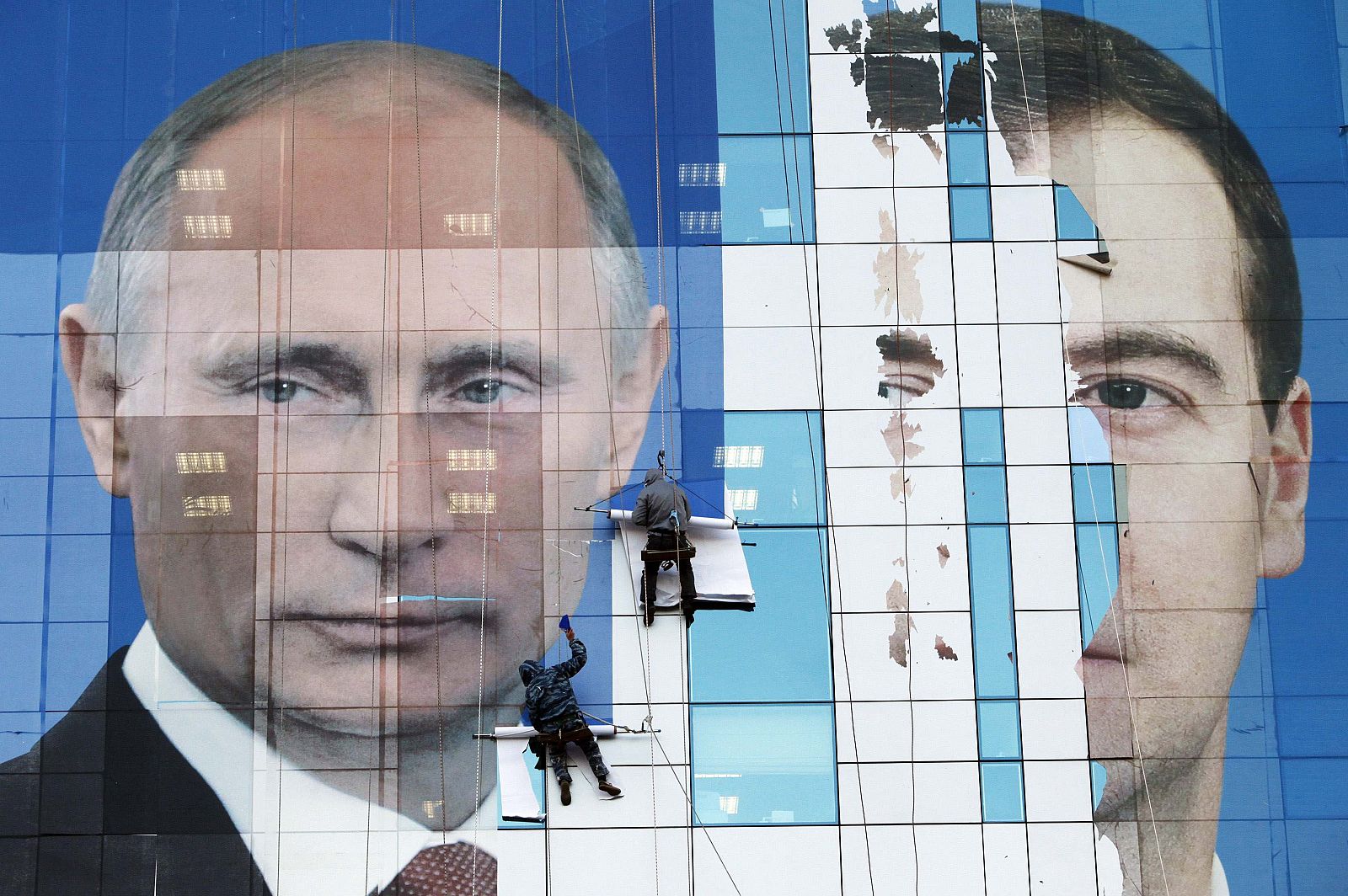 File picture of workers attaching a pre-election poster featuring Medvedev and Putinin in Krasnodar