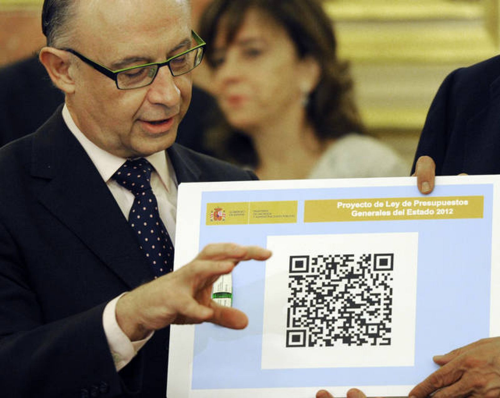 El ministro de Hacienda, Cristobal Montoro, posa junto con el código QR y el pendrive de los Presupuestos Generales del Estado, que fueron presentados este martes en el Congreso de los Diputados