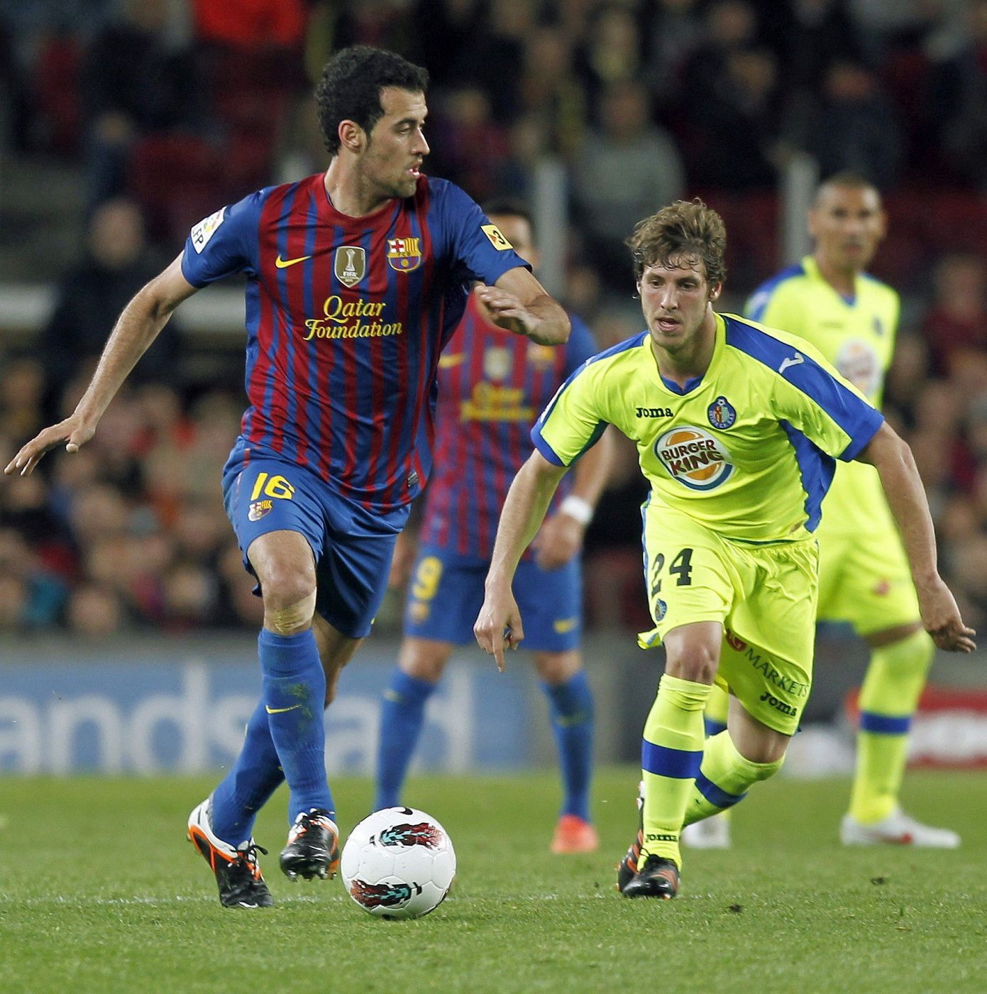 El centrocampista del Barcelona Sergio Busquets (i) intenta controlar un balón ante el centrocampista del Getafe Rubén Pérez.