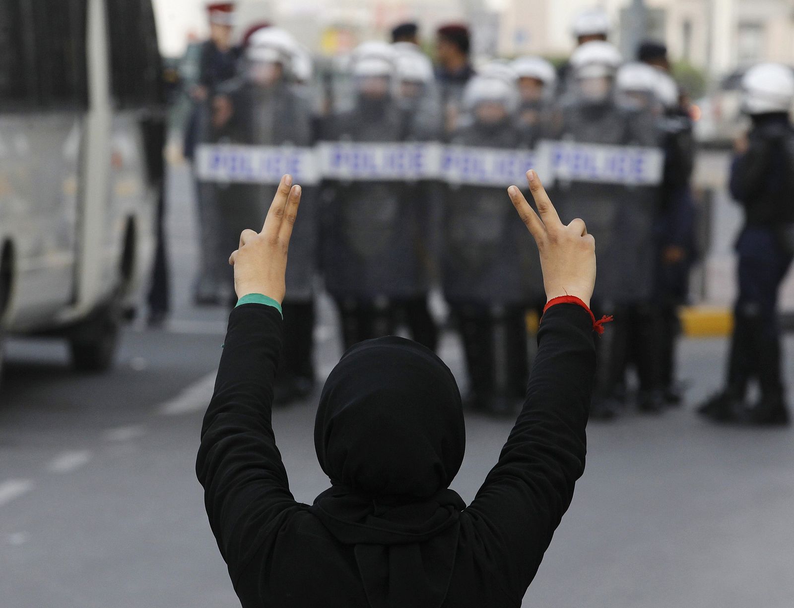 Una manifestante hace el signo de la victoria ante la Policía en la capital de Baréin, Manama