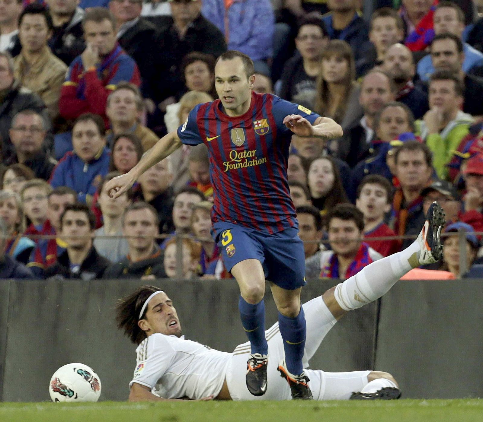 El centrocampista del FC Barcelona Andrés Iniesta elude la entrada del centrocampista alemán del Real Madrid, Sami Khedira