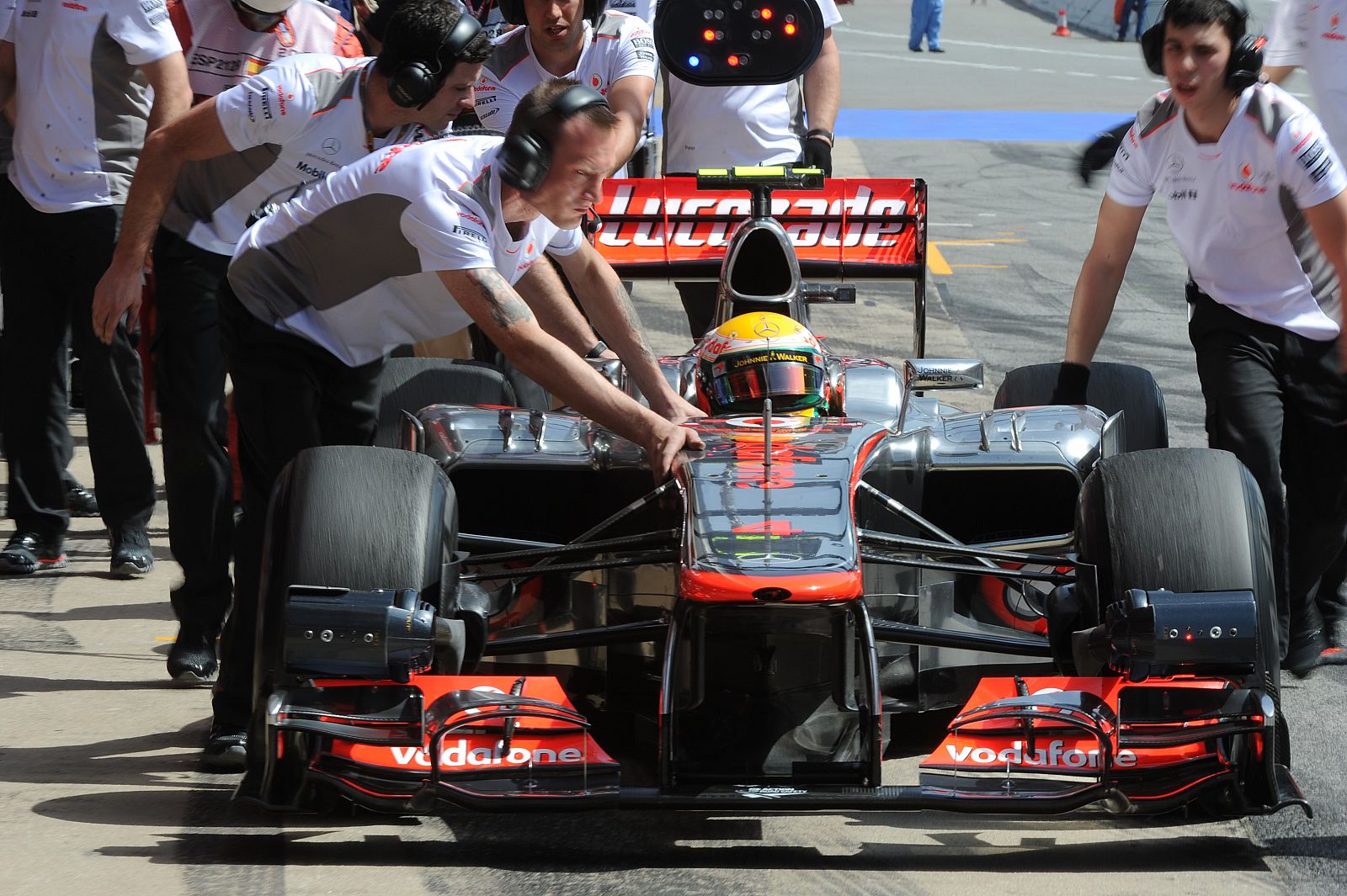 Los mecánicos de McLaren empujan el coche de Hamilton.