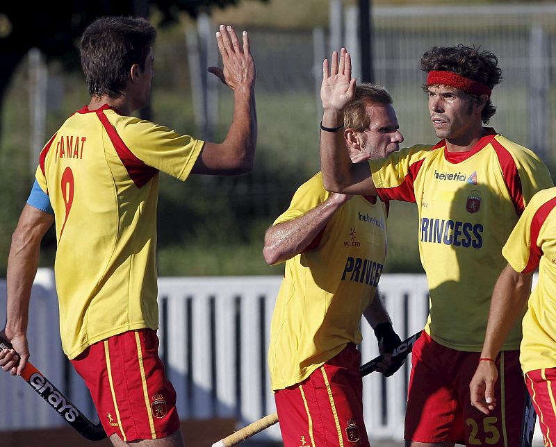 Los jugadores de la selección española de hockey hierba Pol Amat (i) y Ramón Alegre (2 i) felicitan a su compañero Pau Quemada tras marcar ante Gran Bretaña en un amistoso.