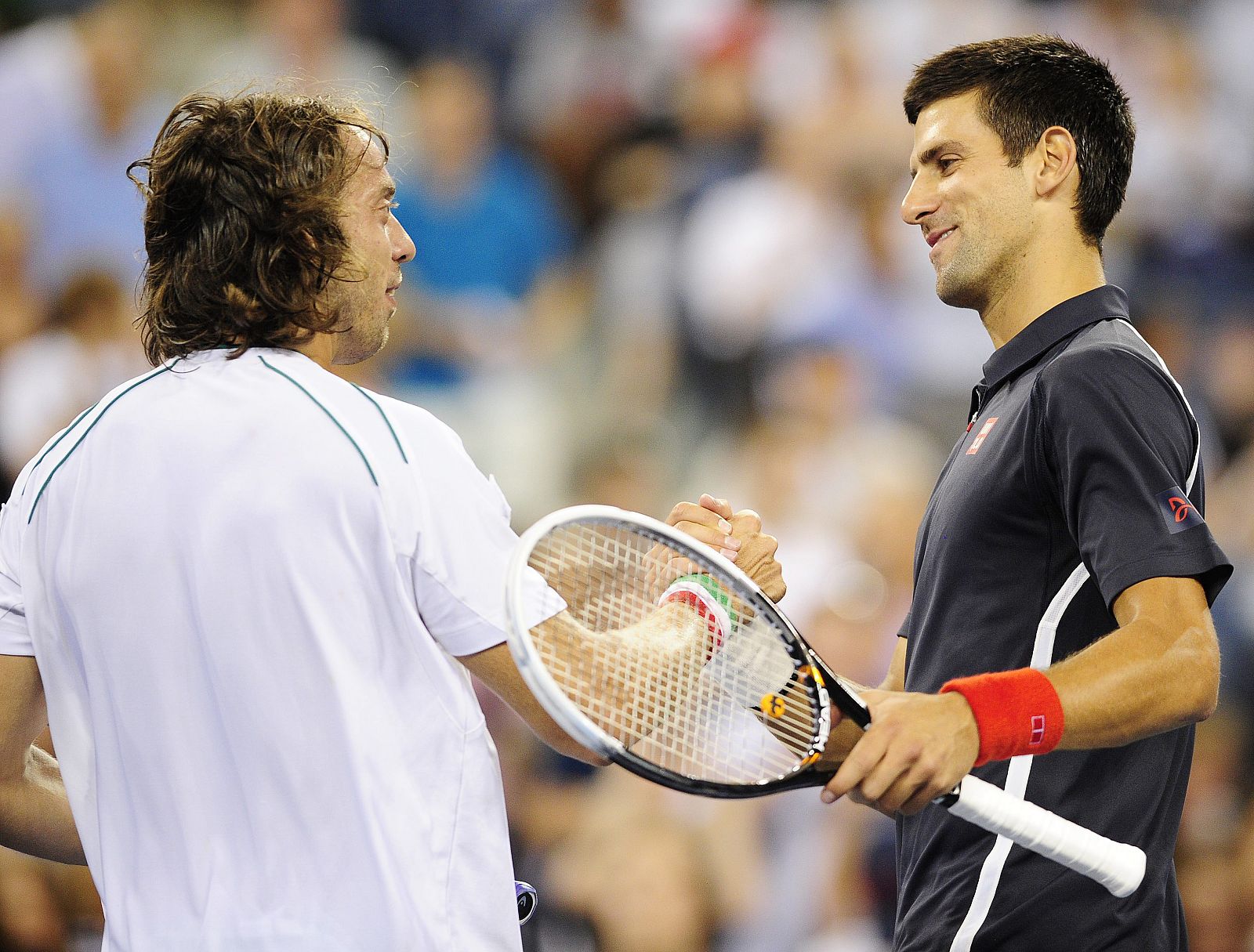 El serbio Novak Djokovic (d) estrecha la mano del italiano Paolo Lorenzi (i) tras su victoria