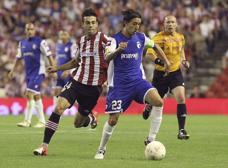 El capitán del Hapoel Kiryat Shmona FC, Adrian Rochet disputa un balón con el delantero del Athletic Club de Bilbao Markel Susaeta.
