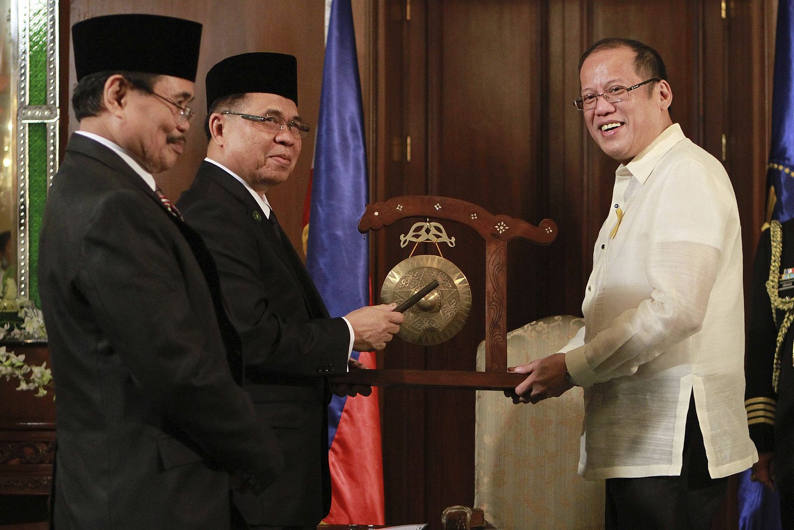 El presidente del Frente Moro de Liberación Islámica (FMLI), Murad Ebrahim (2ºizda), entrega un gong al presidente filipino, Benigno Aquino III, durante la firma del acuerdo
